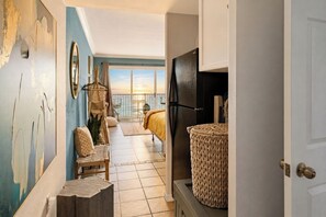 A hotel room with a balcony, a bed, a large woven basket, and a view of the sea.