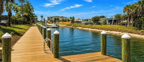 A wooden boardwalk leading to a body of water with a clear sky above.