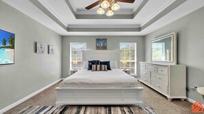 A bedroom with a large bed, a ceiling fan, a dresser, and a window with blinds. - Large and Refreshing 3BR Miramar Beach Family Home (Miramar Beach)