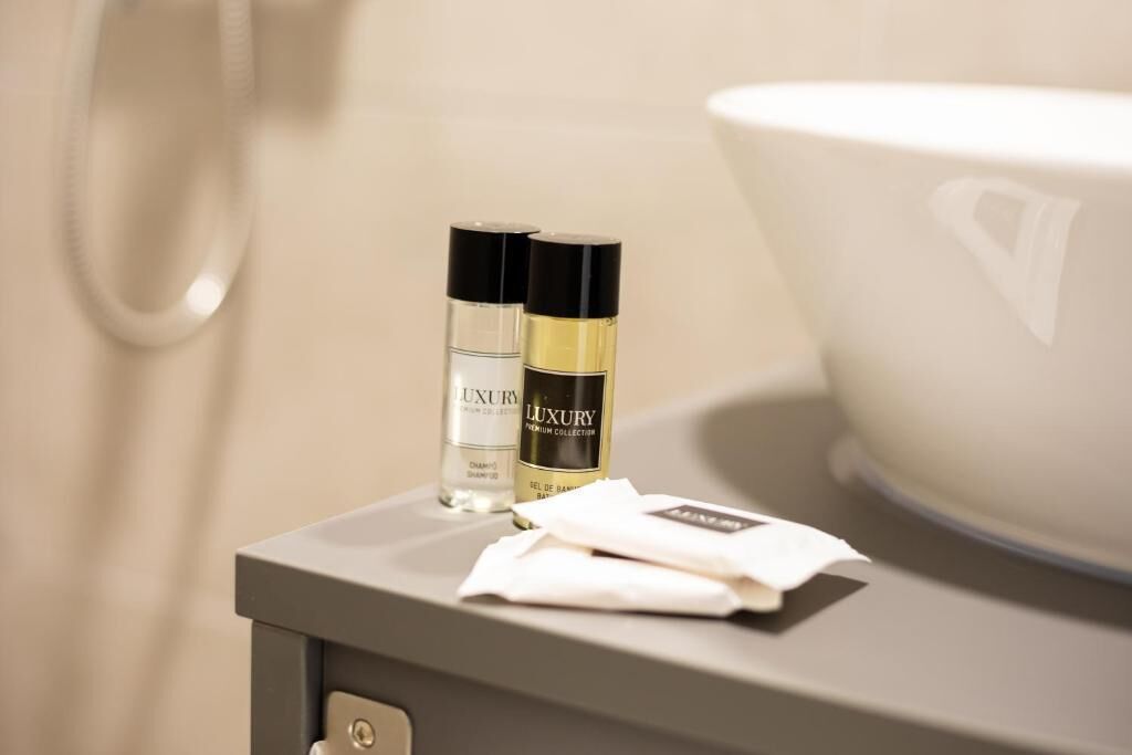 A bathroom vanity with two bottles of luxury shampoo and conditioner, a white towel, and a large white basin.