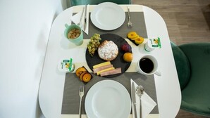 A breakfast setup with a plate of fruit, a pastry, and a cup of coffee on a table. - Porto d'Abrigo - Alojamento Local (Sardoal)