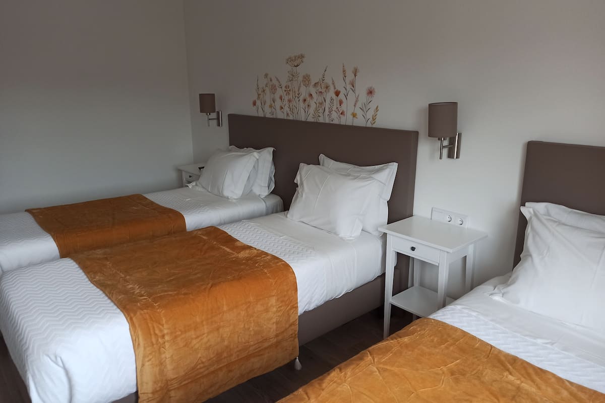 A hotel room with two beds, a nightstand, a desk, and a wall-mounted lamp.