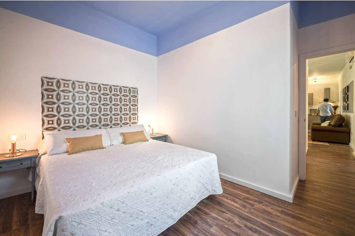Un dormitorio con una cama grande, un cabecero estampado y piso de madera.