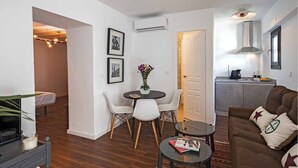 Un espacio habitable compacto con zona de comedor, sofá, cafetera y cocina.