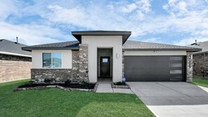 A modern two-story house with a garage, a brick facade, and a well-maintained lawn.