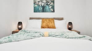 A neatly made bed with a patterned blanket, a wooden headboard, and two bedside lamps.