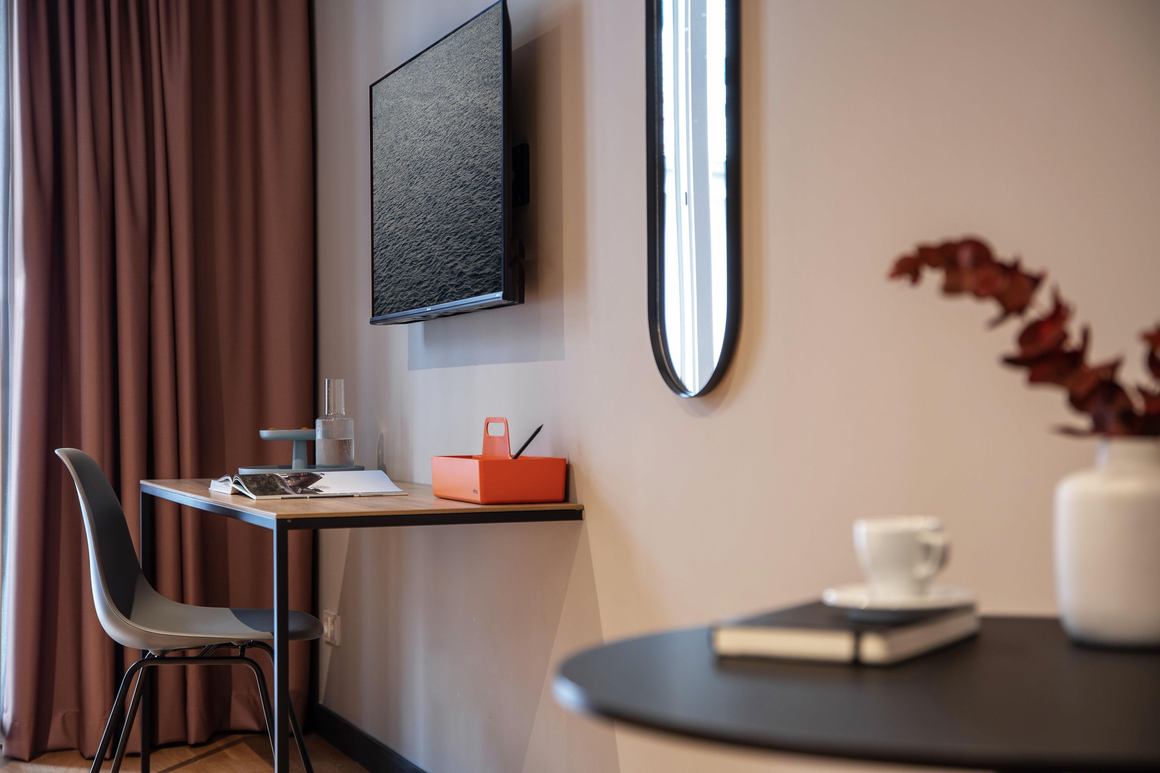 A modern room with a desk, chair, and a small table with a cup and book.