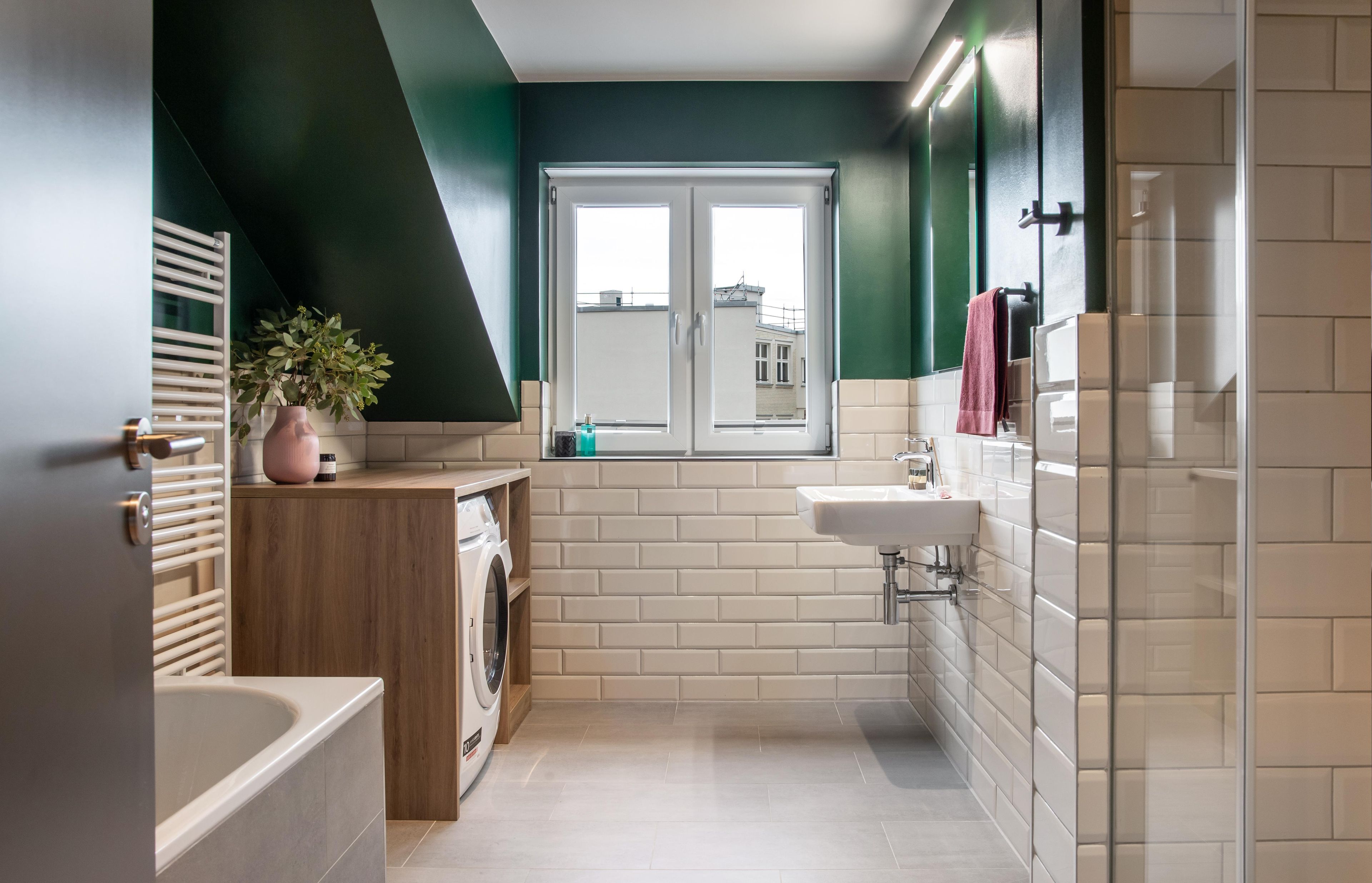 A modern bathroom with a washing machine, a sink, and a window.