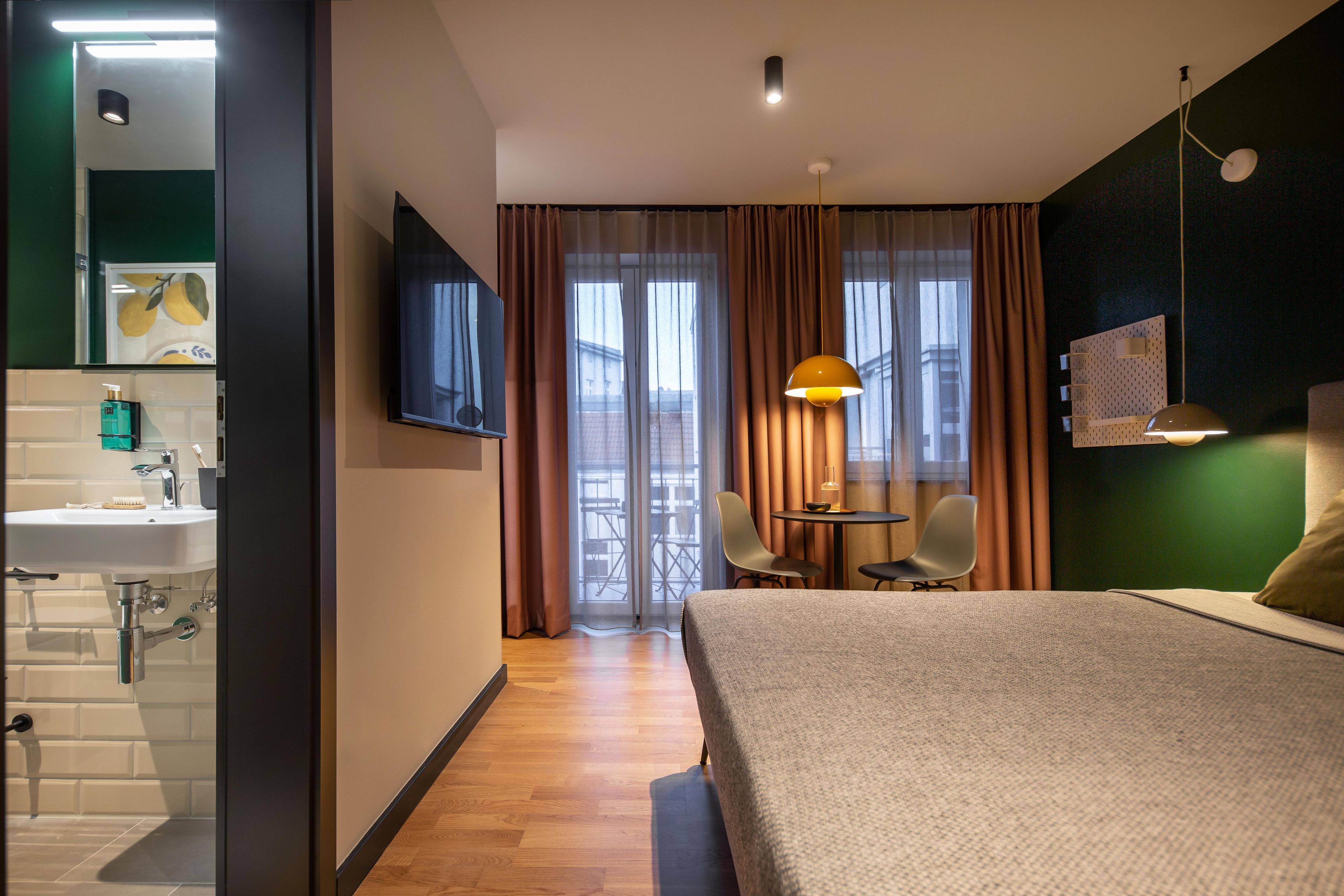 A hotel room with a bed, a desk, a chair, a television, and a bathroom.