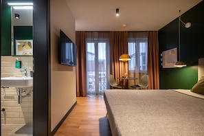 A hotel room with a bed, a desk, a chair, a television, and a bathroom. - ipartment Berlin Mitte @HOME by Best Western (Berlin)