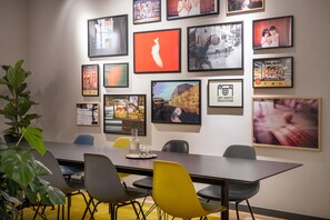 A conference room with a long table, multiple chairs, and framed photographs on the wall. - ipartment Berlin Mitte @HOME by Best Western (Berlin)