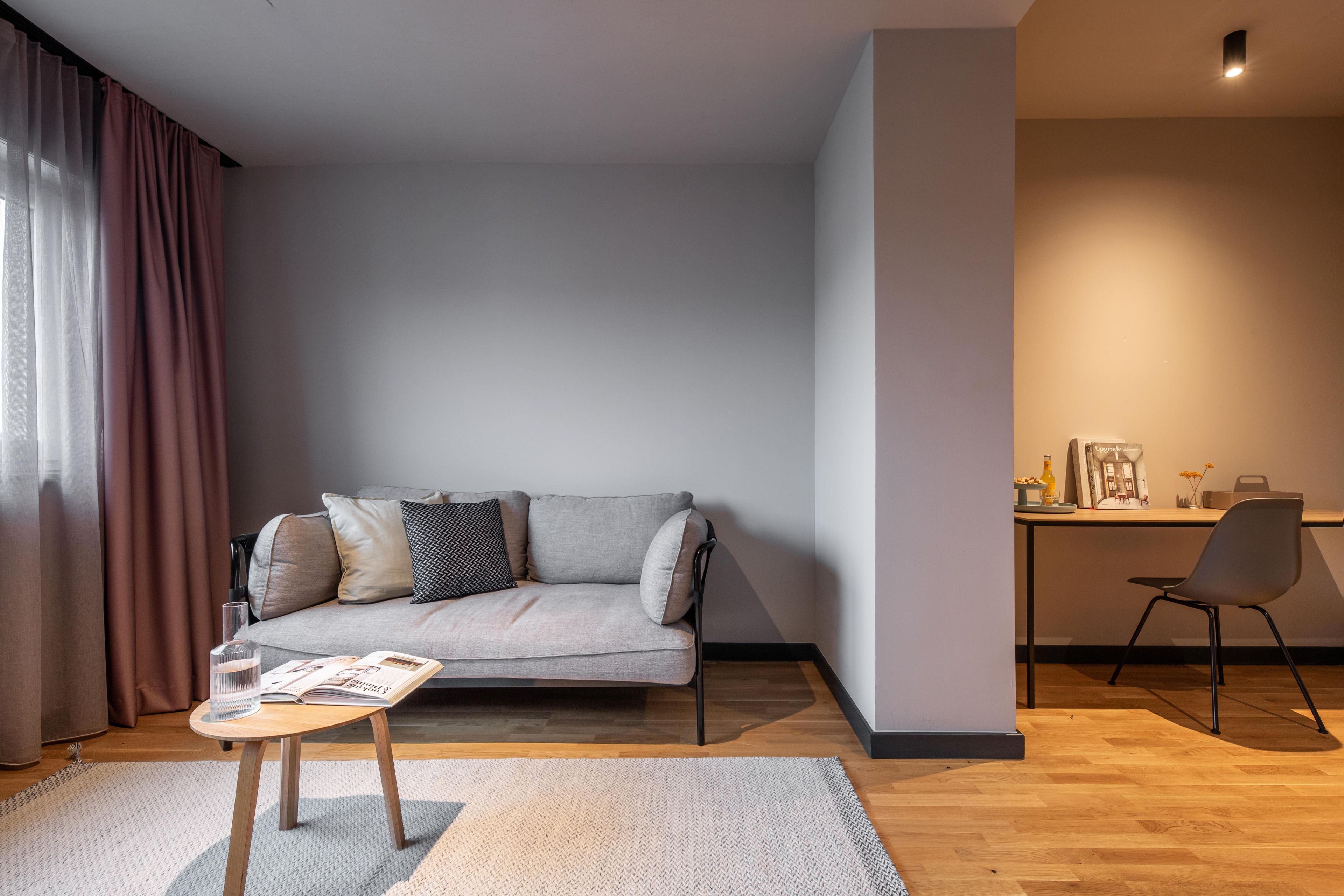 Una sala de estar moderna con un sofá, una mesita, una silla y una zona de escritorio.