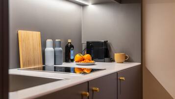 A modern kitchen with a built-in stove, a coffee maker, and a bowl of fruit on the counter.