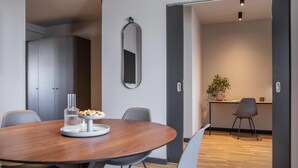 A modern dining area with a round table, chairs, a mirror, and a kitchen in the background. - ipartment Berlin Mitte @HOME by Best Western (Berlin)