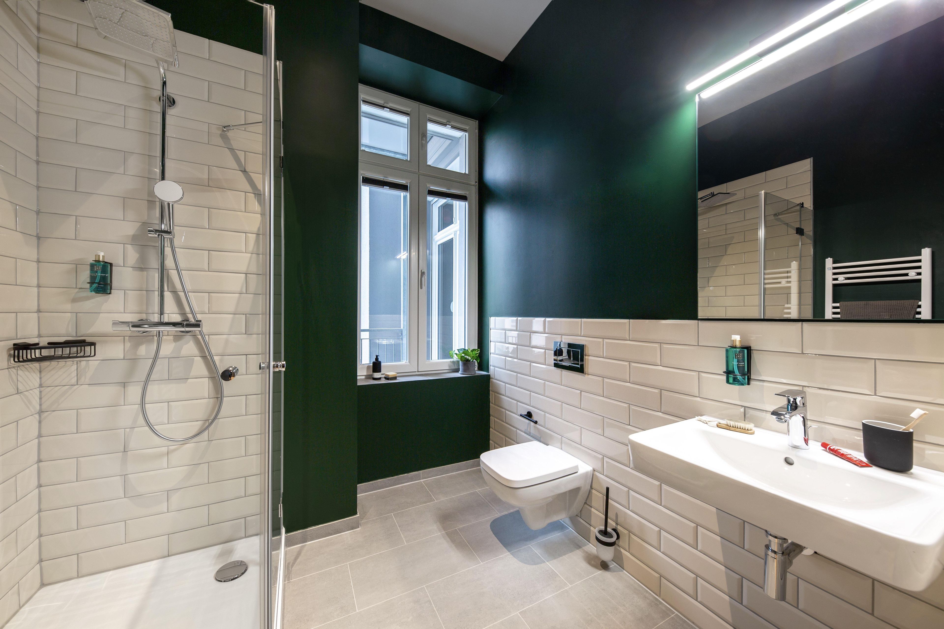 Ein modernes Badezimmer mit Duschkabine aus Glas, einer weißen Toilette und einem Waschbecken mit Spiegel darüber.