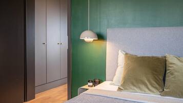 Ein Schlafzimmer mit einem Bett, Kissen, einem Nachttisch, einer Lampe und einem Kleiderschrank.