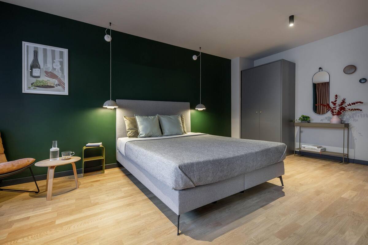 A modern bedroom with a bed, bedside tables, a chair, and a wardrobe.
