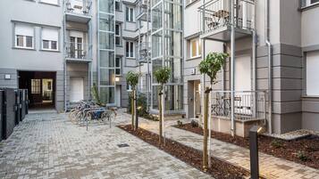 A multi-story residential building with balconies, a bike parking area, and a paved courtyard.