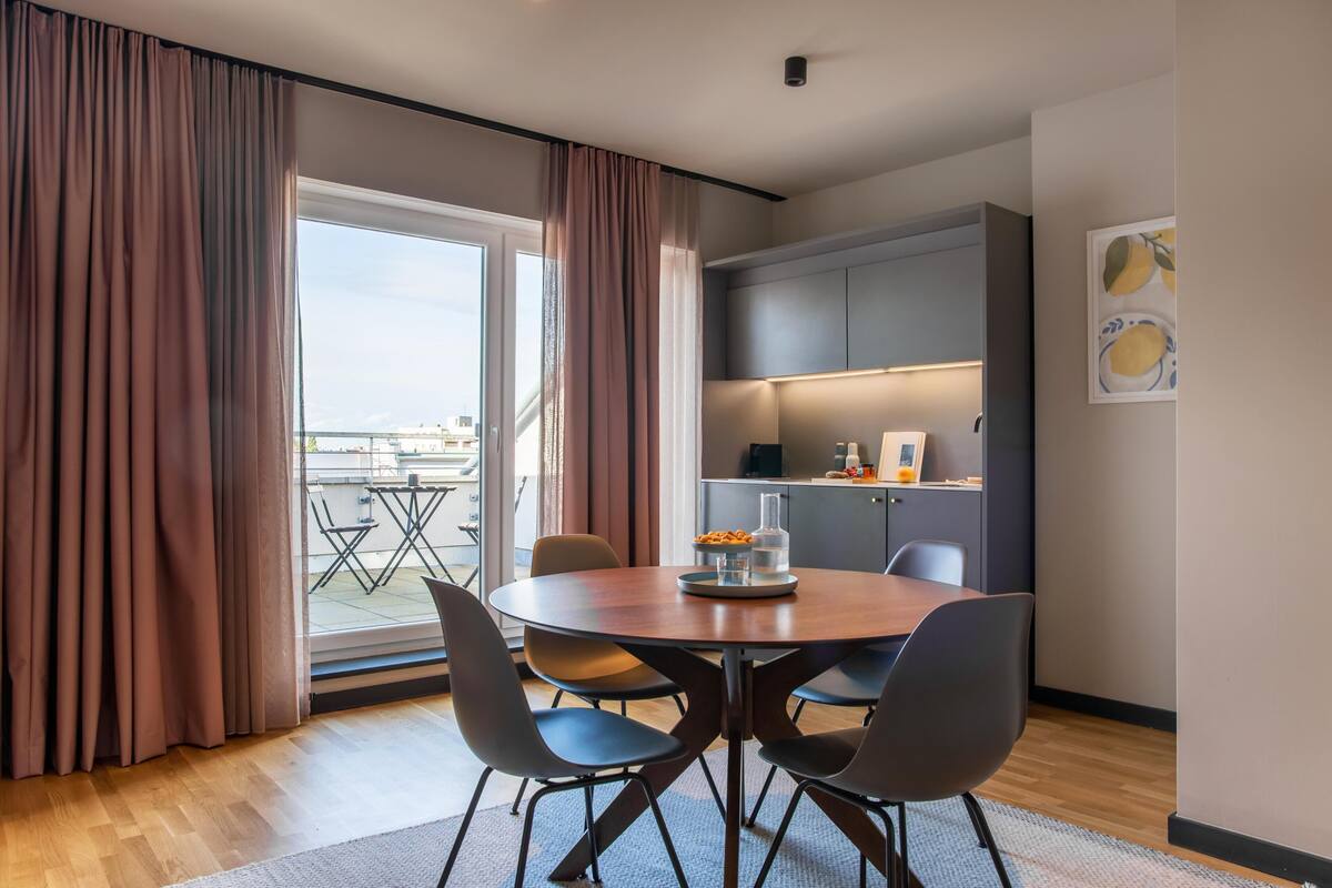 A modern dining area with a round table, four chairs, and a view to the outside.