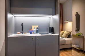 Una cocina moderna con estufa integrada, cafetera y un cuenco de fruta en la encimera.