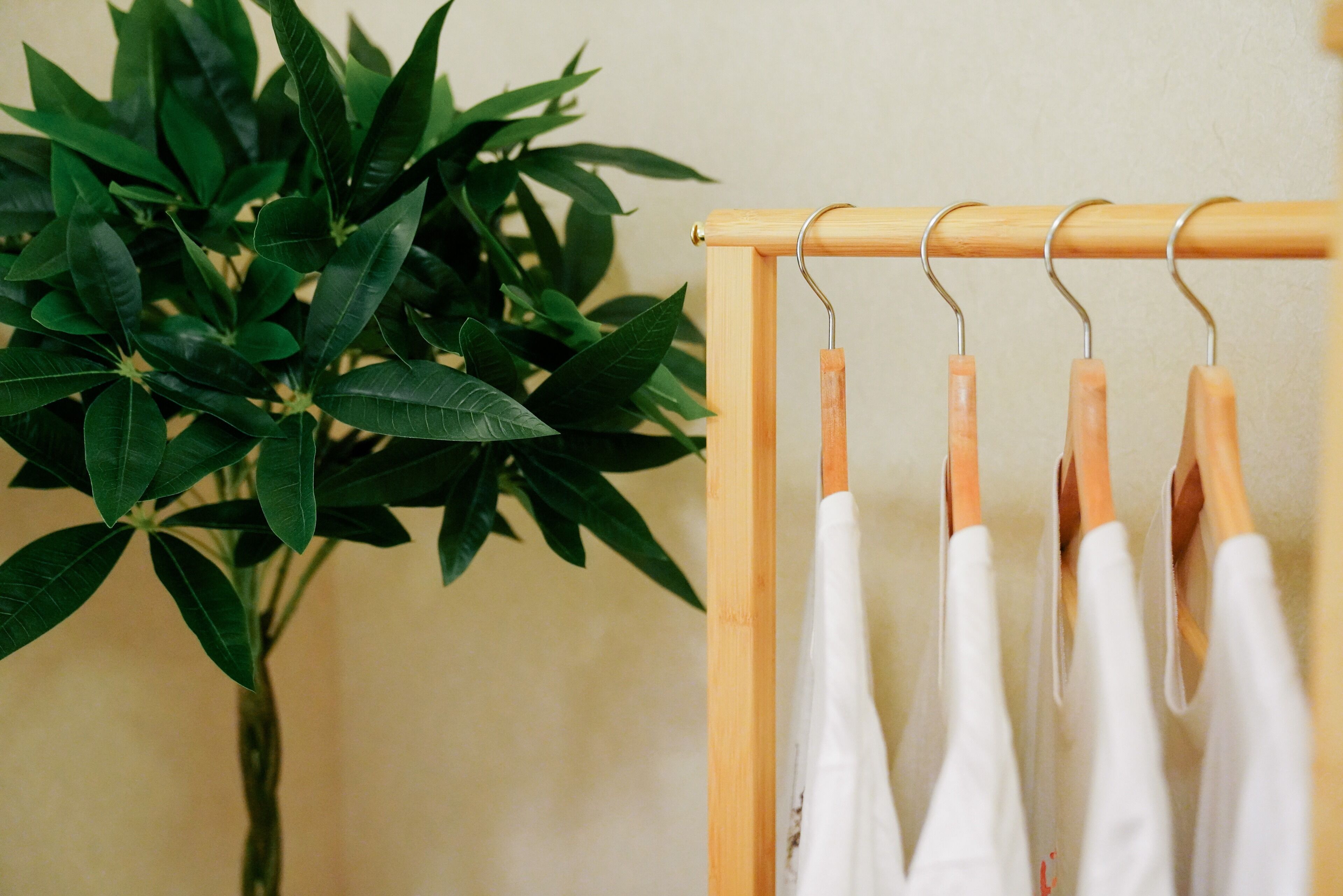 A wooden hanger rack with white garments hanging on it.