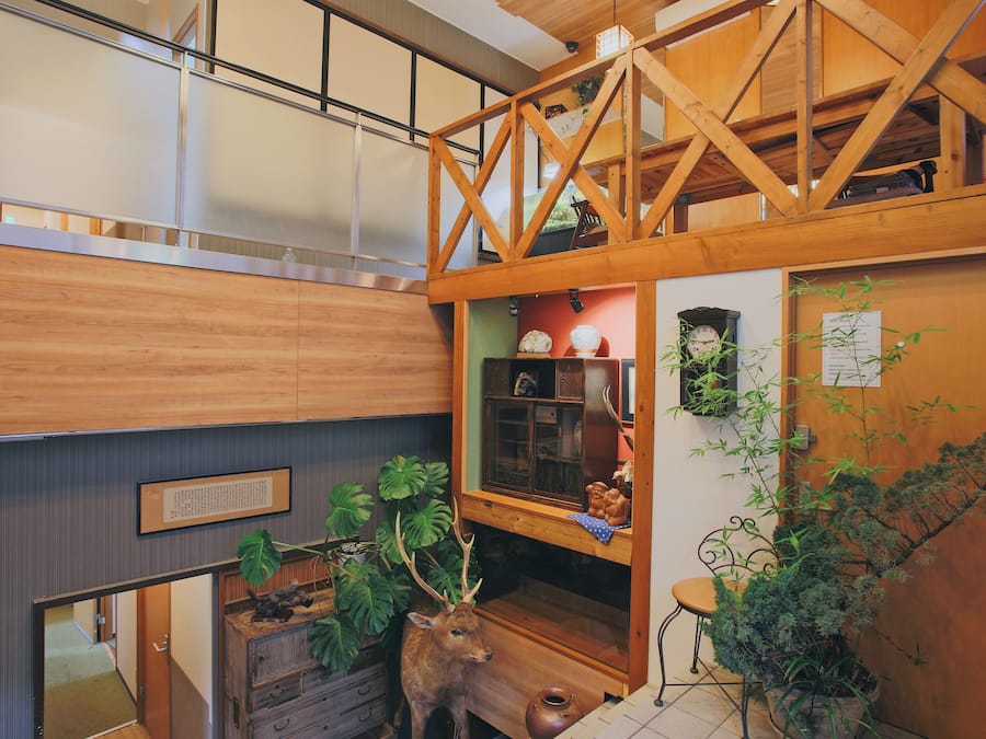 A wooden interior with a loft area, a wooden cabinet, and a deer sculpture.