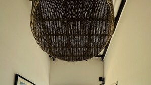 Een kamer met twee houten stoelen gericht op een kleine tuin met planten en uitzicht op een traditioneel gebouw.
