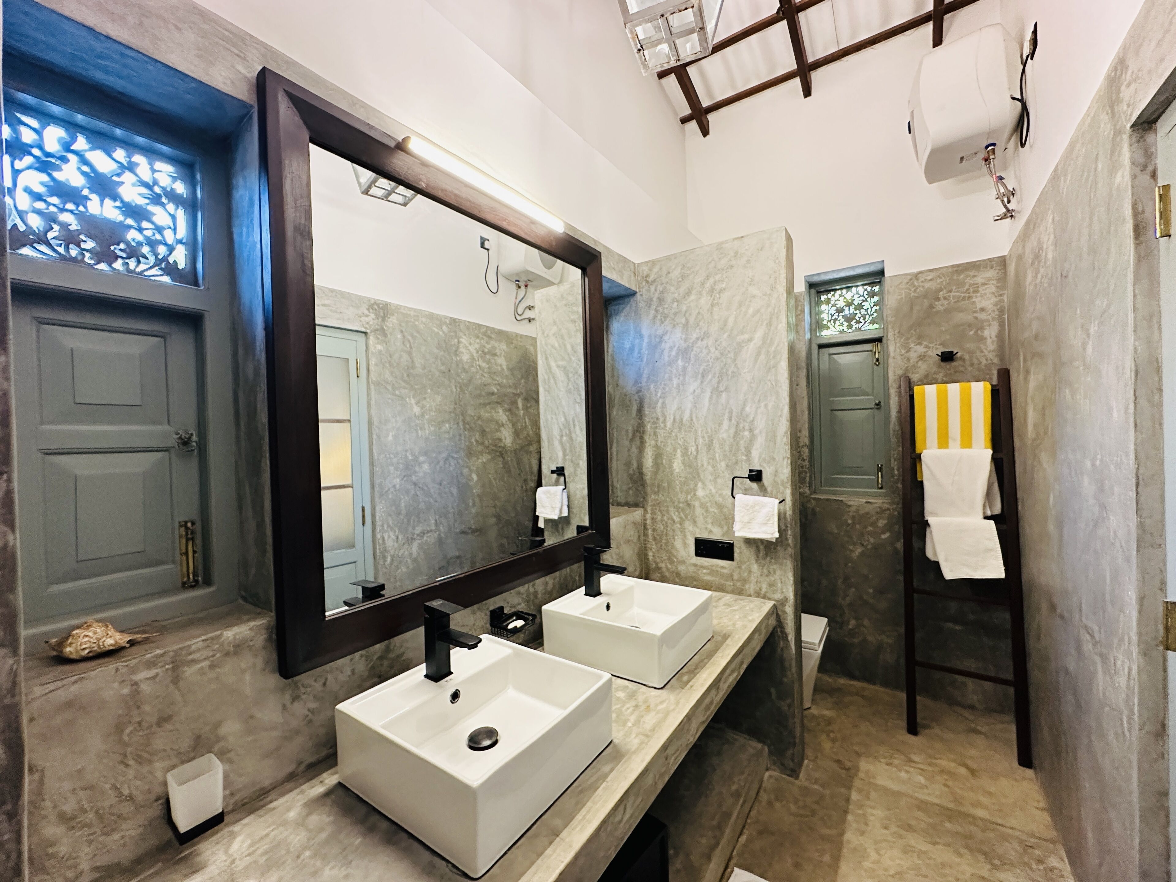 A modern bathroom with two sinks, a large mirror, and a towel rack.