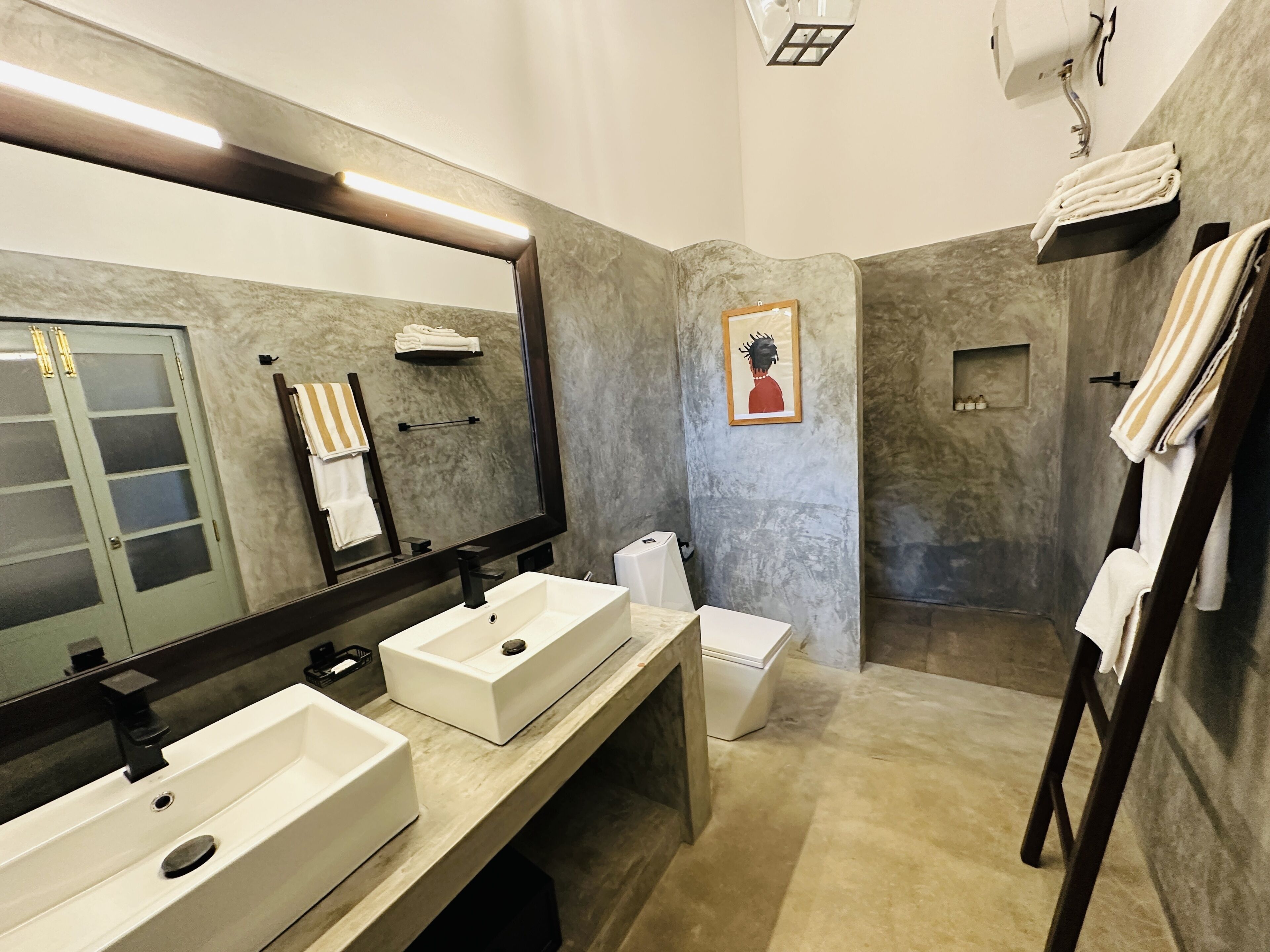 A modern bathroom with two sinks, a large mirror, and a shower area.