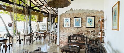 A spacious indoor area with a high ceiling, exposed brick walls, and rustic wooden furniture.