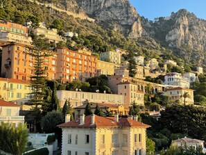 A hillside town with buildings built on terraces, featuring balconies and a mix of architectural styles.