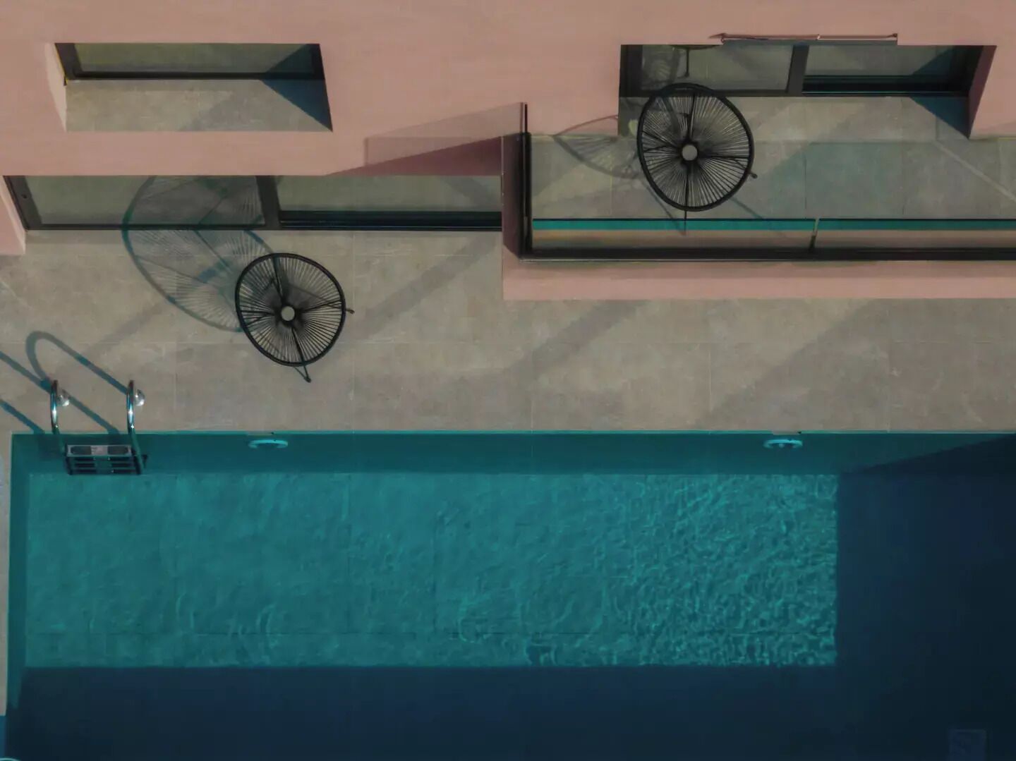 Vista aérea de uma piscina com duas espreguiçadeiras e dois ventiladores.