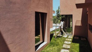 Un edificio moderno con facciata strutturata, un vialetto stretto e un piccolo albero.