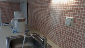 A kitchen with a stainless steel sink, a coffee maker, and a tiled backsplash. - Seaside Nicola's Studio (Matala)