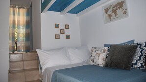 A bedroom with a bed, a world map on the wall, and a window with curtains. - Seaside Nicola's Studio (Matala)