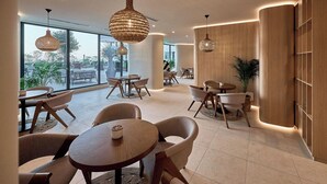 A modern interior with round tables and chairs, large windows, and wooden paneling. - ALEZZI INFINITY RESORT & SPA (Navodari)