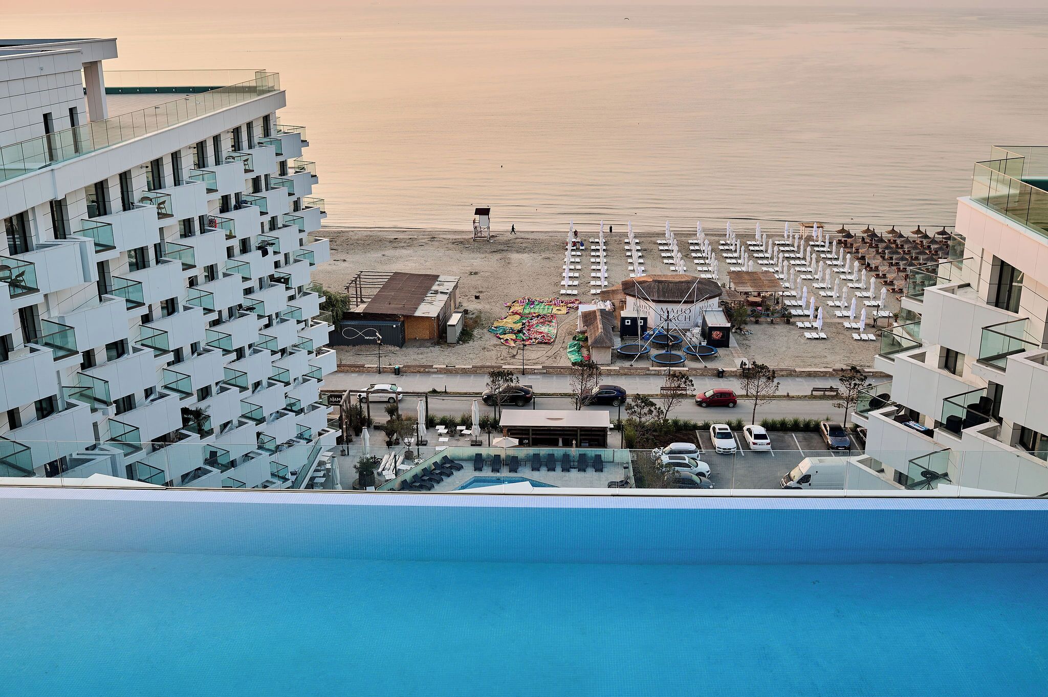 A modern hotel with multiple balconies overlooking a beach.