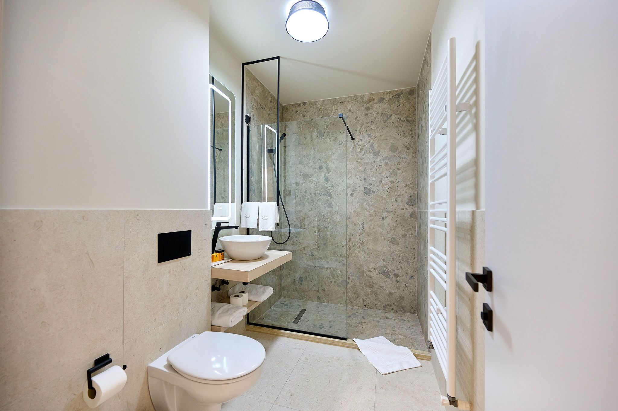 Et moderne badeværelse med toilet, vask og brusebad.