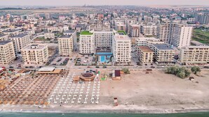 An aerial view of a residential area with multiple apartment buildings, a parking lot, and a beach with sun loungers. - ALEZZI INFINITY RESORT & SPA (Navodari)