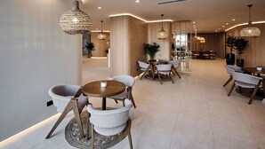 A modern hotel lobby with round tables and chairs, ambient lighting, and a wooden accent wall. - ALEZZI INFINITY RESORT & SPA (Navodari)