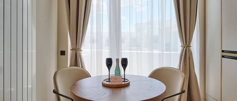 A round dining table with two chairs, a bottle of champagne, and two glasses on a tray.