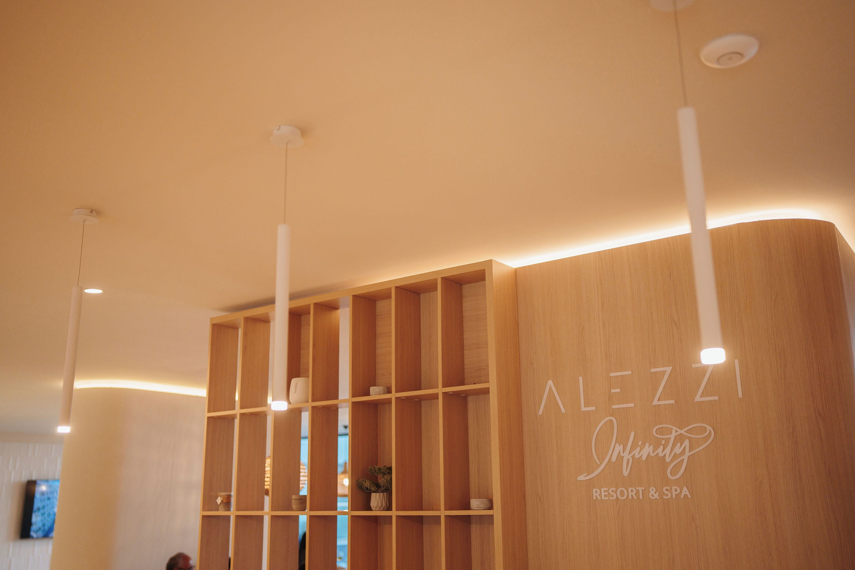 Un comptoir d’accueil en bois sur lequel est apposée une enseigne indiquant : « ALEZZI Infinity Resort & Spa ».