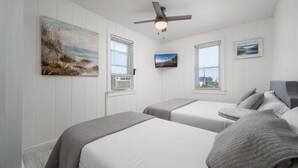 A bedroom with two beds, a ceiling fan, a TV, and artwork on the walls. - Two bedroom ocean block condo in a great location! (Ocean City)