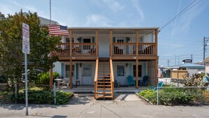 A two-story building with a wooden balcony, a flag, and a sign indicating no parking on the street. - Two bedroom ocean block condo in a great location! (Ocean City)