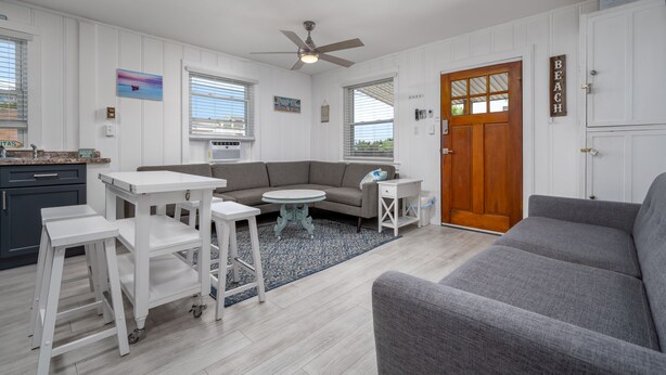 A modern living room with a gray sofa, white tables, and a ceiling fan. - Two bedroom ocean block condo in a great location! (Ocean City)