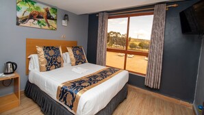 A hotel room with a large bed, a painting of a leopard, a TV, and a view of the outdoors. - Eaglesvale Hotel (Naivasha)