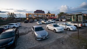 A parking lot with multiple cars, a building with a sign for Eaglevale Resort, and a billboard advertising Guinness beer. - Eaglesvale Hotel (Naivasha)