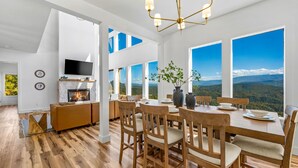 A dining area with a wooden table and chairs, a fireplace, and large windows offering a mountain view. - Elegant Cabin | Indoor Pool, Dog-Friendly (Sevierville)