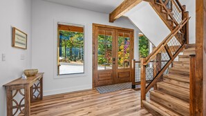 A wooden staircase with a metal railing leading to a door with an American flag. - Elegant Cabin | Indoor Pool, Dog-Friendly (Sevierville)