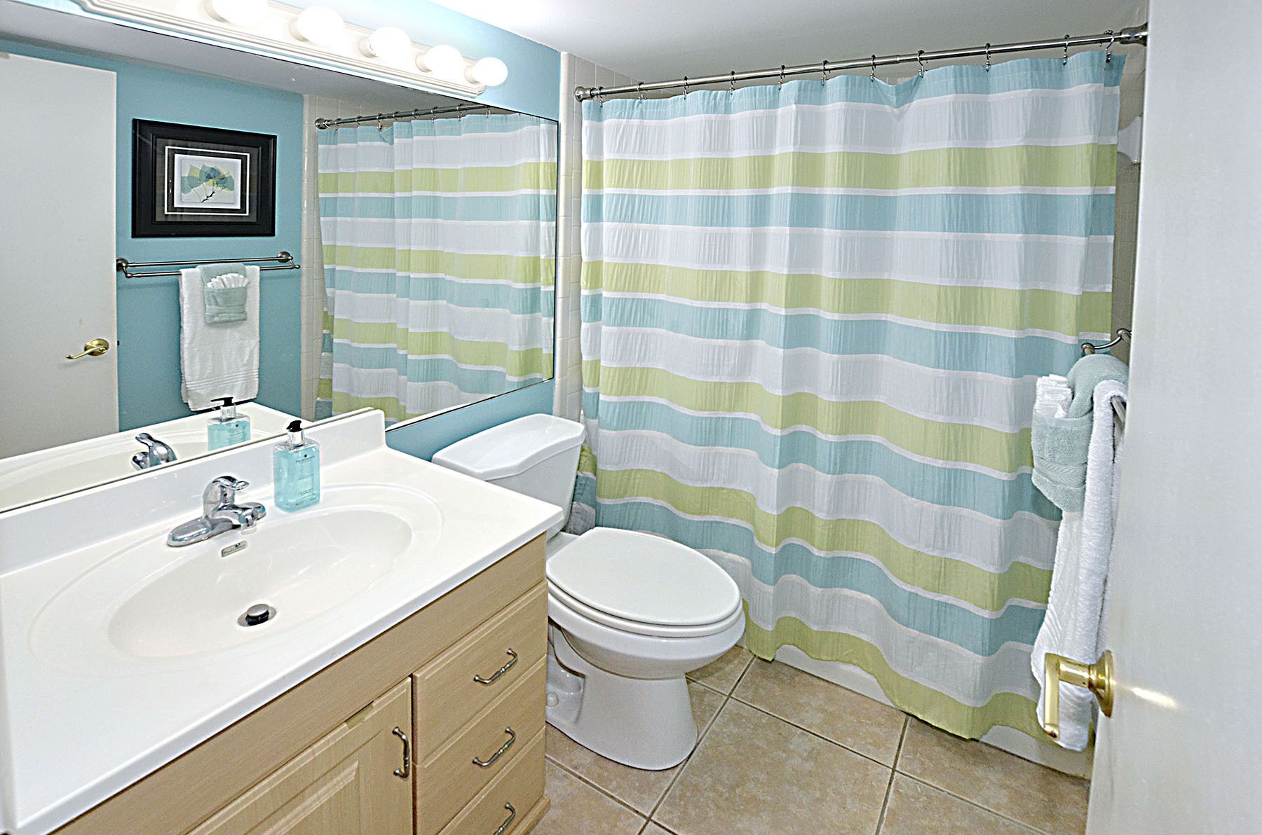 A bathroom with a striped shower curtain, a white sink, and a toilet.